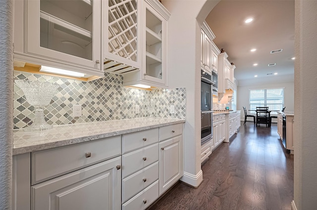 19415 Maifest Dr, Cypress, TX 77433 - kitchen with arched walkways, dark wood-style floors, white cabinets, decorative backsplash, and double oven
