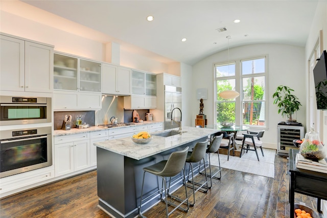 5007 Dickson St, Houston, TX 77007 - kitchen with stainless steel appliances, wine cooler, vaulted ceiling, dark wood finished floors, and light stone counters