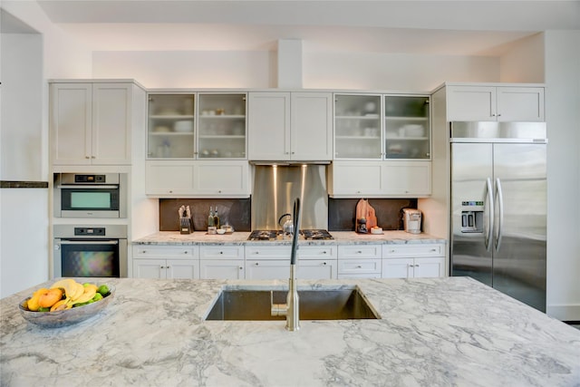 5007 Dickson St, Houston, TX 77007 - kitchen with stainless steel appliances, light stone countertops, decorative backsplash, glass insert cabinets, and white cabinetry
