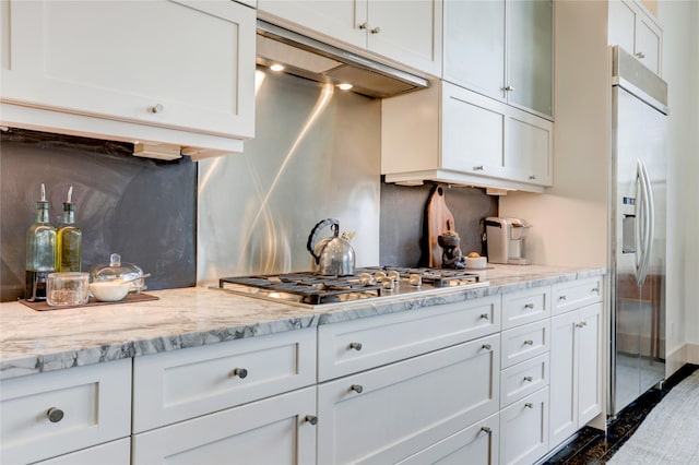 5007 Dickson St, Houston, TX 77007 - kitchen with under cabinet range hood, stainless steel gas stovetop, built in fridge, and white cabinets