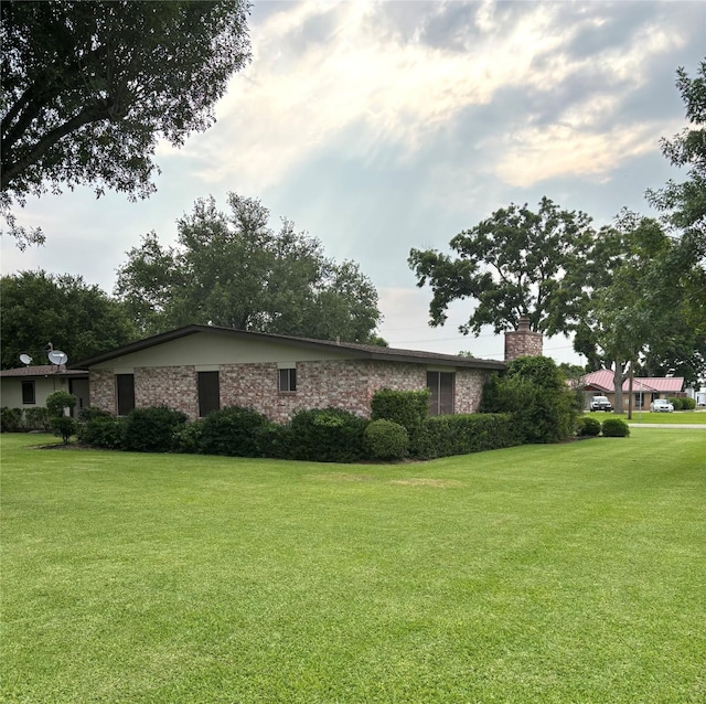 103 Greenbriar Dr, Wharton, TX 77488 - view of home's exterior featuring a chimney, a lawn, and brick siding