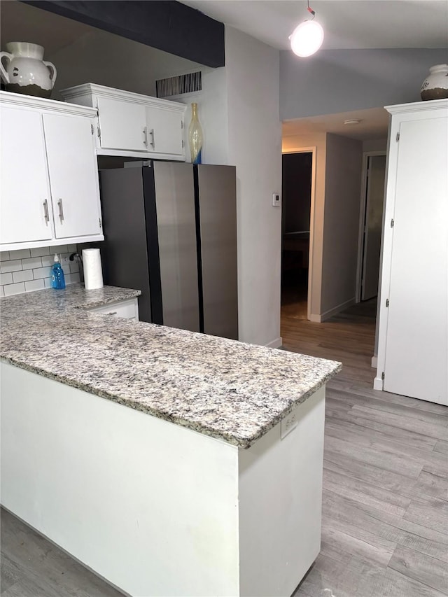 103 Greenbriar Dr, Wharton, TX 77488 - kitchen featuring freestanding refrigerator, a peninsula, white cabinetry, light stone countertops, and light wood-type flooring