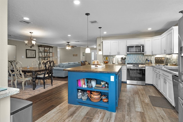 3926 Lavender St, Houston, TX 77026 - kitchen with stainless steel appliances, white cabinetry, dark wood-style flooring, open floor plan, and decorative backsplash