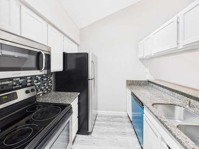 8055 Cambridge St Unit 26, Houston, TX 77054 - kitchen featuring appliances with stainless steel finishes, decorative backsplash, vaulted ceiling, light wood-type flooring, and white cabinets