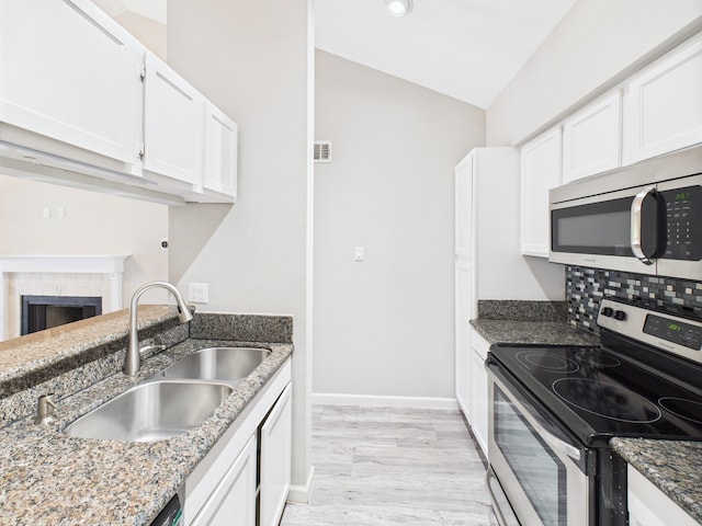 8055 Cambridge St Unit 26, Houston, TX 77054 - kitchen featuring stainless steel appliances, light wood finished floors, dark stone countertops, white cabinetry, and lofted ceiling