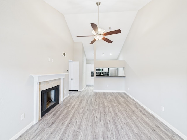 8055 Cambridge St Unit 26, Houston, TX 77054 - unfurnished living room featuring ceiling fan, high vaulted ceiling, light wood-style floors, and a tile fireplace