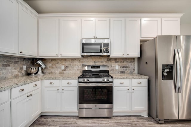 3053 Peterson Cir, Bryan, TX 77802 - kitchen with stainless steel appliances, white cabinetry, tasteful backsplash, and light wood-type flooring