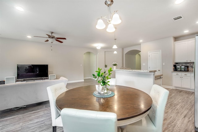 3053 Peterson Cir, Bryan, TX 77802 - dining space featuring arched walkways, light wood finished floors, a ceiling fan, recessed lighting, and a chandelier