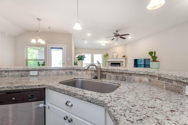 3053 Peterson Cir, Bryan, TX 77802 - kitchen featuring stainless steel dishwasher, ceiling fan, white cabinets, hanging light fixtures, and a fireplace