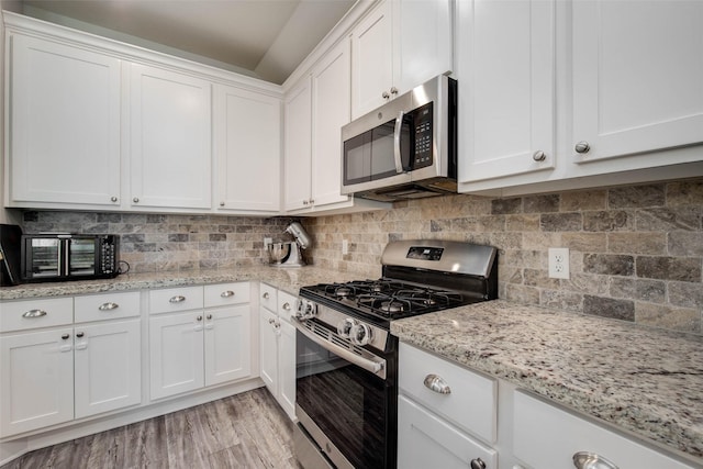 3053 Peterson Cir, Bryan, TX 77802 - kitchen with stainless steel appliances, white cabinetry, light wood finished floors, and backsplash