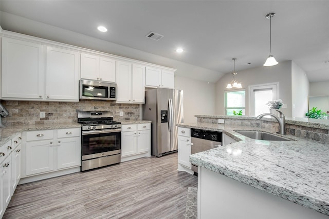 3053 Peterson Cir, Bryan, TX 77802 - kitchen featuring appliances with stainless steel finishes, white cabinetry, backsplash, lofted ceiling, and light wood finished floors