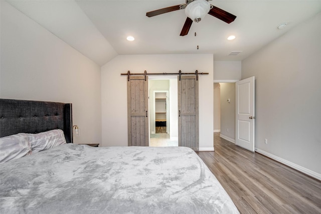 3053 Peterson Cir, Bryan, TX 77802 - bedroom with a barn door, wood finished floors, recessed lighting, ceiling fan, and vaulted ceiling