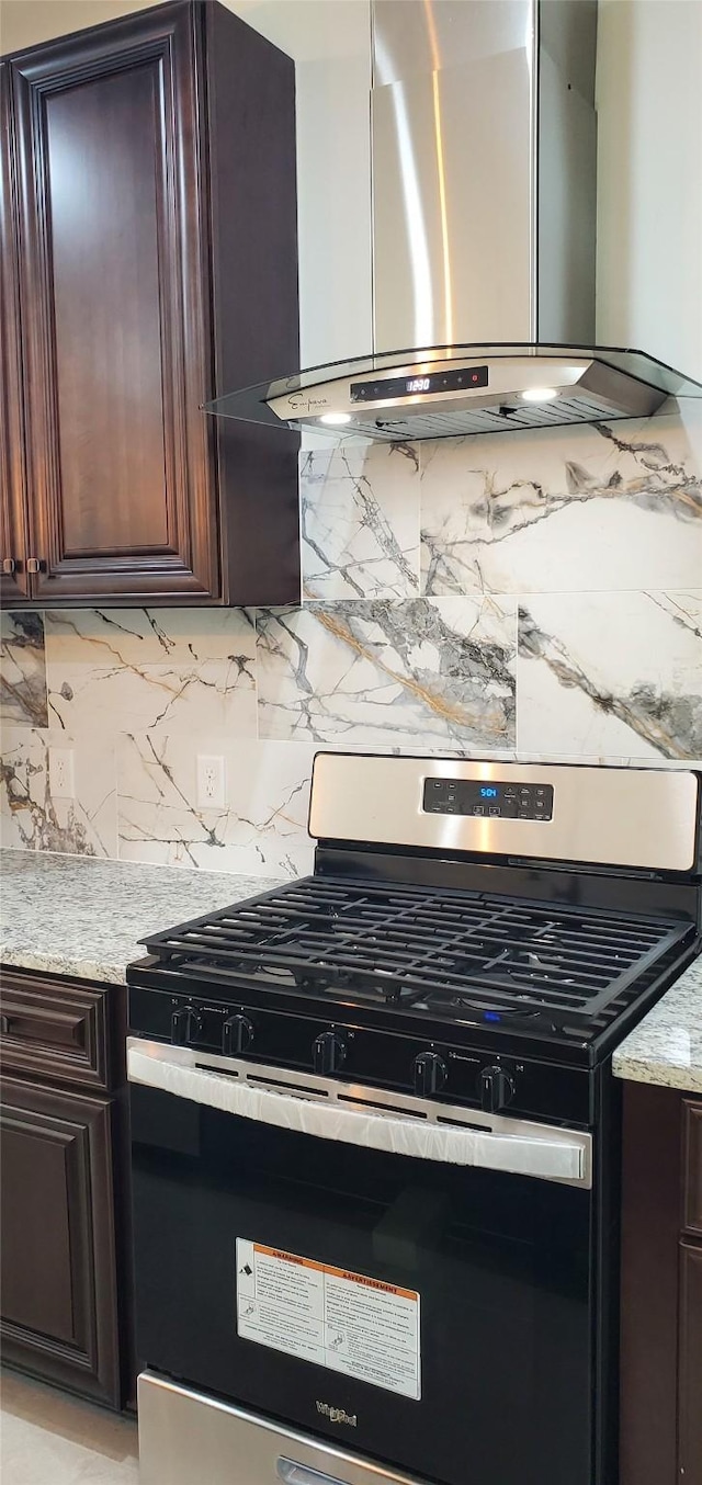 4209 Tampico Rd, Houston, TX 77016 - kitchen featuring stainless steel gas range oven, range hood, backsplash, dark brown cabinets, and light stone counters