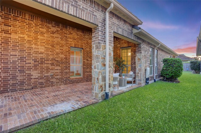 4023 Turning Manor Ln, Sugar Land, TX 77479 - property exterior at dusk with a yard, brick siding, and a patio