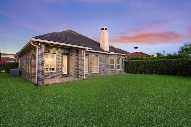 4023 Turning Manor Ln, Sugar Land, TX 77479 - back of house at dusk featuring a yard, brick siding, and a chimney