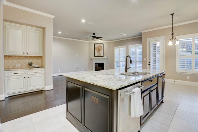 4023 Turning Manor Ln, Sugar Land, TX 77479 - kitchen with stainless steel dishwasher, a ceiling fan, decorative backsplash, light stone counters, and a fireplace