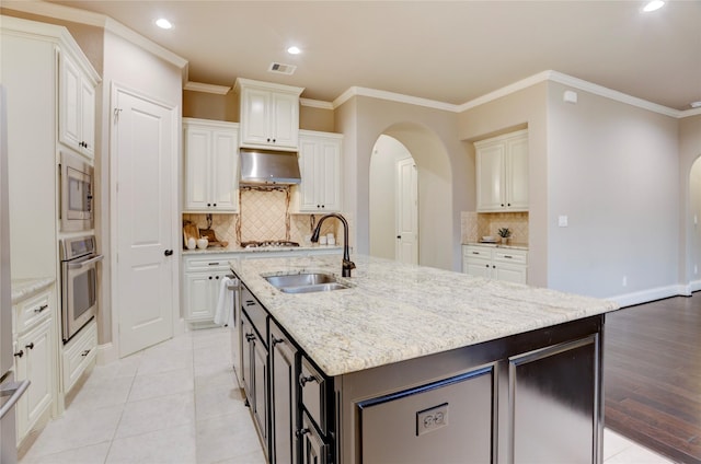4023 Turning Manor Ln, Sugar Land, TX 77479 - kitchen with appliances with stainless steel finishes, arched walkways, under cabinet range hood, ornamental molding, and white cabinets
