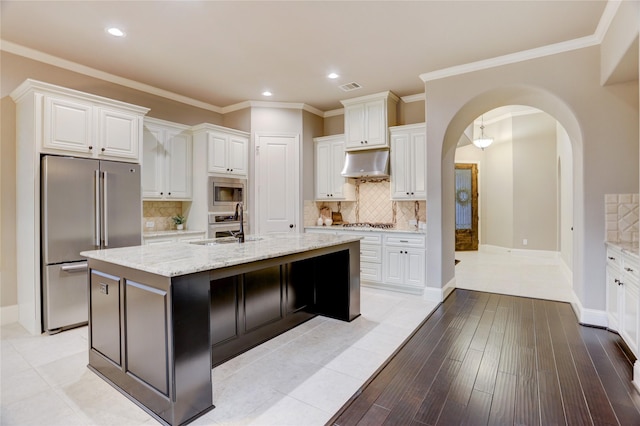 4023 Turning Manor Ln, Sugar Land, TX 77479 - kitchen featuring appliances with stainless steel finishes, under cabinet range hood, arched walkways, white cabinets, and recessed lighting