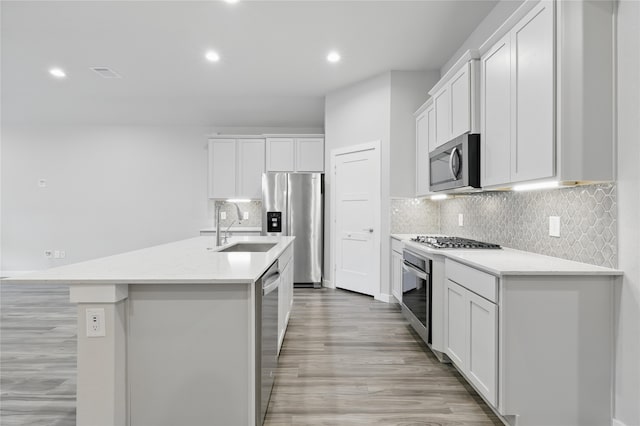 10026 Angelina Woods Ln, Conroe, TX 77384 - kitchen featuring appliances with stainless steel finishes, recessed lighting, light countertops, a kitchen island with sink, and white cabinetry