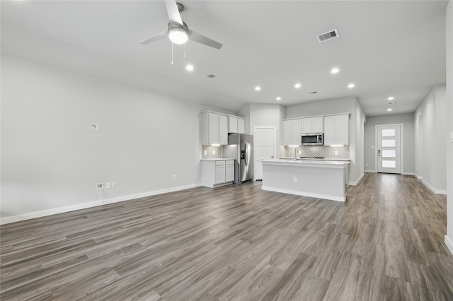 10026 Angelina Woods Ln, Conroe, TX 77384 - unfurnished living room with wood finished floors, ceiling fan, and recessed lighting