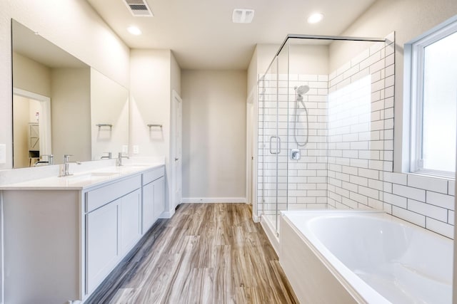 10026 Angelina Woods Ln, Conroe, TX 77384 - bathroom featuring a bath, a shower stall, double vanity, wood finished floors, and recessed lighting