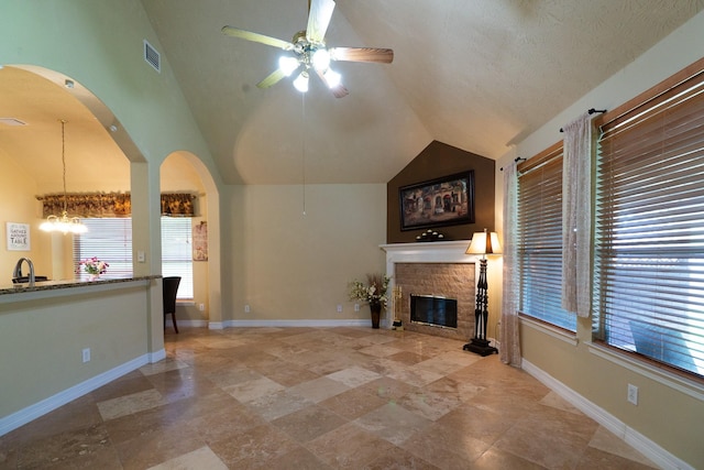 22110 Nobles Crossing Dr, Spring, TX 77373 - unfurnished living room with lofted ceiling, ceiling fan, a glass covered fireplace, a chandelier, and arched walkways