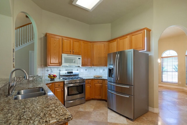 22110 Nobles Crossing Dr, Spring, TX 77373 - kitchen featuring stainless steel appliances, stone countertops, arched walkways, backsplash, and a peninsula