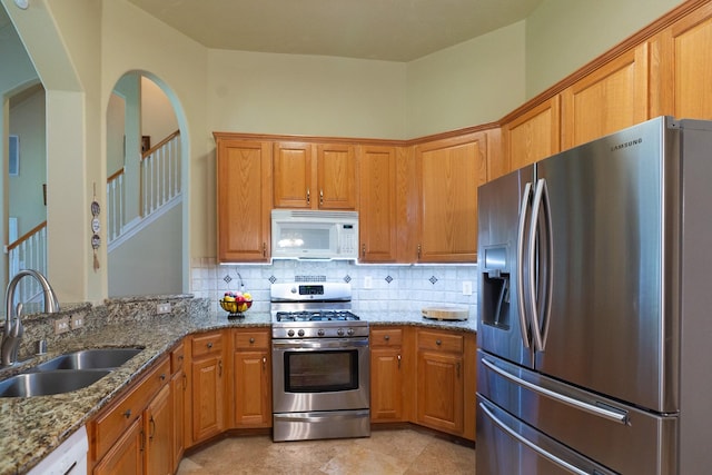 22110 Nobles Crossing Dr, Spring, TX 77373 - kitchen featuring stainless steel appliances, backsplash, stone counters, arched walkways, and brown cabinetry