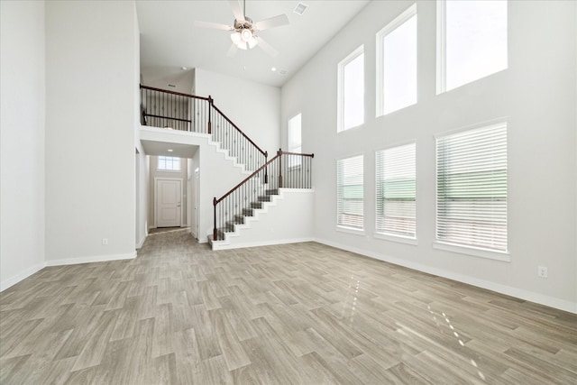 7838 Ruth Ravine Ct, Spring, TX 77379 - unfurnished living room featuring a high ceiling, light wood-type flooring, stairway, and ceiling fan