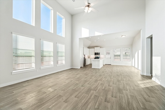 7838 Ruth Ravine Ct, Spring, TX 77379 - unfurnished living room with a towering ceiling, a ceiling fan, and light wood finished floors