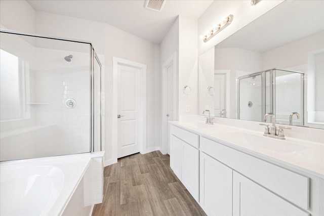 7838 Ruth Ravine Ct, Spring, TX 77379 - bathroom featuring a stall shower, double vanity, a garden tub, and wood finished floors