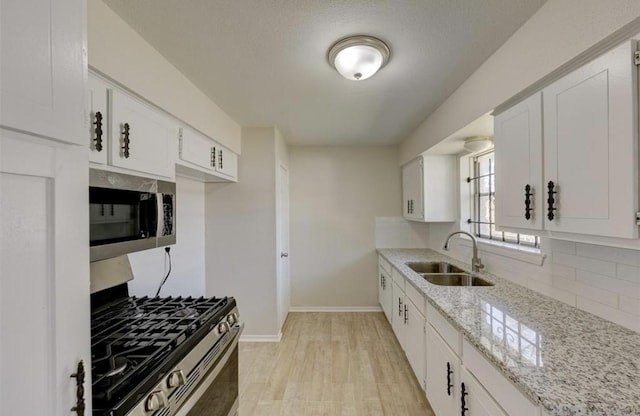 12938 S Coast Dr, Houston, TX 77047 - kitchen with appliances with stainless steel finishes, backsplash, light wood finished floors, light stone countertops, and white cabinetry