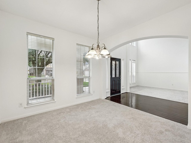 421 White Oak Pointe, League City, TX 77573 - spare room with dark colored carpet, a chandelier, arched walkways, and plenty of natural light