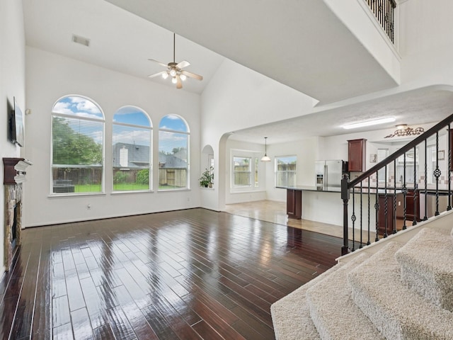 421 White Oak Pointe, League City, TX 77573 - unfurnished living room with a ceiling fan, high vaulted ceiling, wood finished floors, arched walkways, and stairs