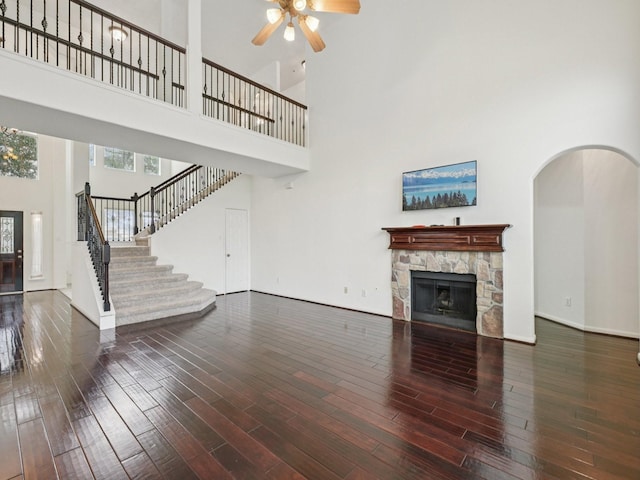 421 White Oak Pointe, League City, TX 77573 - unfurnished living room with a towering ceiling, ceiling fan, wood finished floors, stairway, and a stone fireplace