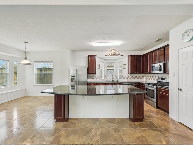 421 White Oak Pointe, League City, TX 77573 - kitchen featuring stainless steel appliances, backsplash, a kitchen island, dark stone countertops, and decorative light fixtures