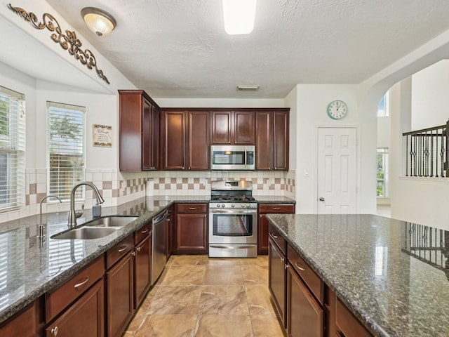 421 White Oak Pointe, League City, TX 77573 - kitchen with stainless steel appliances, arched walkways, dark stone countertops, tasteful backsplash, and a textured ceiling