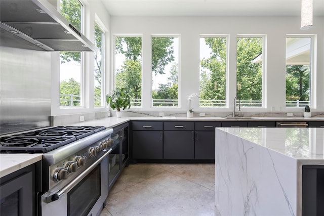 543 Threlkeld St, Houston, TX 77007 - kitchen featuring high end stainless steel range oven, under cabinet range hood, plenty of natural light, and light stone countertops
