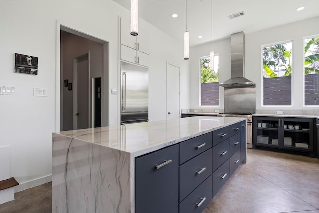 543 Threlkeld St, Houston, TX 77007 - kitchen with wall chimney exhaust hood, premium appliances, finished concrete flooring, white cabinets, and light stone counters