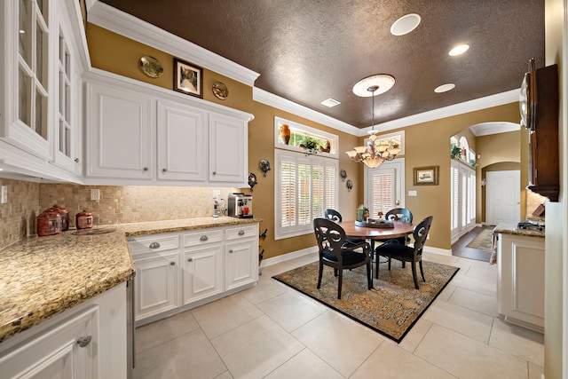 1310 Whispering Pines Dr, Houston, TX 77055 - dining area featuring arched walkways, a chandelier, ornamental molding, light tile patterned flooring, and a textured ceiling