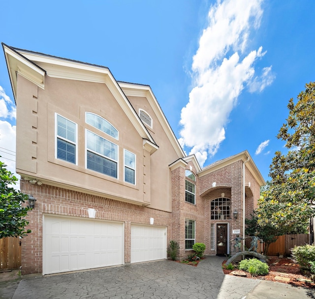 1310 Whispering Pines Dr, Houston, TX 77055 - view of front facade with brick siding, a garage, stucco siding, and driveway