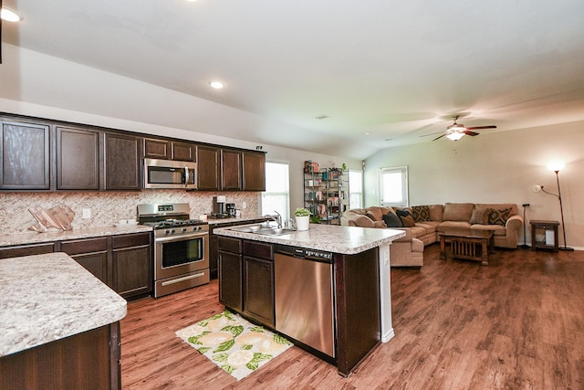 5502 Peralta Mills Way, Katy, TX 77449 - kitchen featuring appliances with stainless steel finishes, dark brown cabinetry, light countertops, wood finished floors, and backsplash