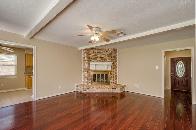 15622 Sunset Rock Dr, Houston, TX 77084 - unfurnished living room with a ceiling fan, wood finished floors, a fireplace, beam ceiling, and a textured ceiling