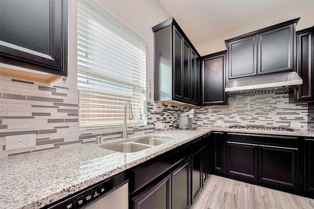 11023 Honey Suckle Haven Dr, Cypress, TX 77433 - kitchen featuring stainless steel appliances, under cabinet range hood, decorative backsplash, dark cabinetry, and light stone countertops