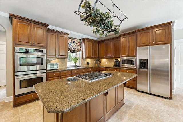 15410 Stable Star Cir, Cypress, TX 77429 - kitchen with stainless steel appliances, dark stone countertops, decorative backsplash, a center island, and ornamental molding