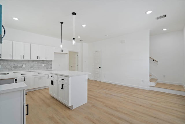 7504 Laura Koppe Rd C/D, Unit C/D Houston, TX 77028 - kitchen with backsplash, white cabinets, light wood-type flooring, light countertops, and decorative light fixtures