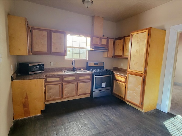 7209 Ave K, Houston, TX 77011 - kitchen featuring gas stove, under cabinet range hood, dark wood-style floors, brown cabinets, and dark countertops