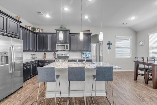 6423 Hunters Creek Ln, Baytown, TX 77521 - kitchen featuring stainless steel appliances, light wood-style floors, a breakfast bar area, tasteful backsplash, and vaulted ceiling