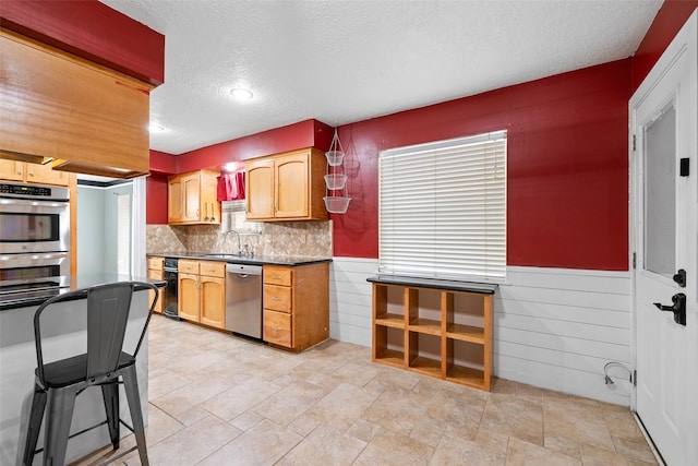 6702 Seinfeld Ct, Houston, TX 77069 - kitchen with stainless steel appliances, a textured ceiling, wainscoting, dark countertops, and backsplash