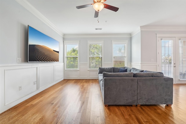 2802 Morrison St Unit 203, Houston, TX 77009 - living room featuring light wood-style flooring, crown molding, a ceiling fan, wainscoting, and a decorative wall